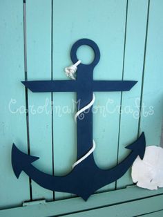 an anchor is on the side of a blue wooden wall next to a seashell