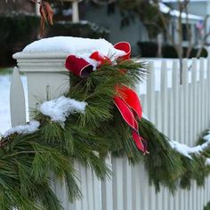 a white picket fence covered in snow and christmas wreath