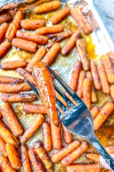 there is a fork that is holding up some carrots in the air frying pan