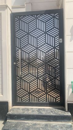 a black door with an intricate design on it's side and steps leading up to the entrance