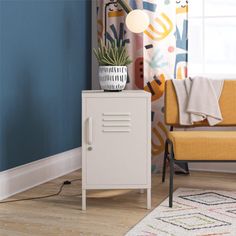 a white cabinet sitting in front of a window next to a yellow chair and potted plant