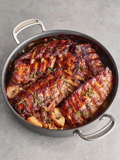 a pan filled with meat and vegetables sitting on top of a cement counter next to a knife