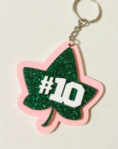 a pink and green glittered keychain with the number 10 on it's side