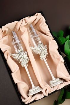 two champagne flutes with pearls and bows in a gift box