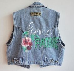 Inspired by all the Femme Fatale's out there. This is a thrifted women’s denim vest in a size M. I hand painted the flowers and the script and added a patch and brass studs to the front. This piece can be machine washed on gentle or hand washed and hang to dry. All vests and jackets are one of a kind. Spring Cotton Vest For Streetwear, Spring Streetwear Cotton Vest, Denim Vest For Spring Streetwear, Trendy Streetwear Vest For Spring, Cotton Vest With Graphic Print For Spring, Trendy Graphic Print Vest For Spring, Cotton Grunge Denim Vest For Spring, Fitted Denim Vest For Spring Streetwear, Spring Cotton Distressed Vest