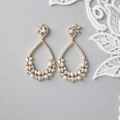 These earrings feature a teardrop-shaped hoop adorned with a charming cluster of pearls, pear, and marquise cut CZ jewels on the lower half. Boasting a length of 2.25 inches, these earrings have titanium post backs and are crafted from rhodium or gold plated brass with AAA CZ stones. Plus, they are lead, nickel, and cadmium free for a worry-free and luxurious accessory. Bridal Jewelry With Lace Dress, Rustic Wedding Earrings, Teardrop Bridal Earrings, 2025 Wedding, Black And White Earrings, Weaving Ideas, Gold Bridal Earrings, Eye Makeup Designs, Bride Accessories