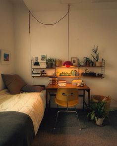 a small bedroom with a bed, desk and shelves on the wall next to it