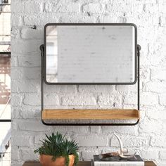 a white brick wall with a wooden shelf and mirror on it next to a potted plant