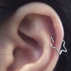 a woman's ear is shown with a small silver nose pin in the middle