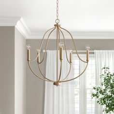 a chandelier hanging from a ceiling in a living room with curtains and windows