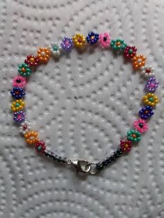 a colorful beaded bracelet with a silver clasp on a white cloth covered tablecloth