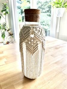 a crocheted vase sitting on top of a wooden table next to a window