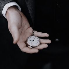 a person in a suit holding an old pocket watch