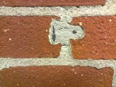 a close up of a brick wall with a small hole in the middle and a dog's head drawn on it