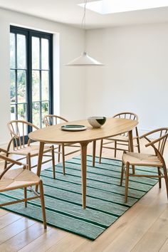 a dining room table with chairs and a bowl on it in front of a large window