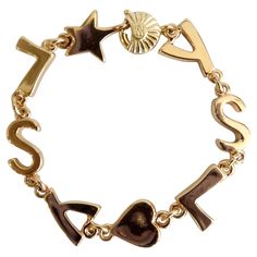 No one does eye candy like Yves Saint Laurent! This is an incredible and hard to find statement YSL logo bracelet from none other than the house of Yves Saint Laurent. This bracelet is straight out of the 1980s and the house of Yves Saint Laurent. This is a vibrant gold plated bracelet that features the iconic "YSL" initials in subtle bubble letters. It features other quirky details by breaking up the "YSL" with a heart and star pendant. Includes a signed spring ring closure. In even better news Ysl Jewelry, Gold Bra, Vintage Charm Bracelet, Ysl Logo, Bubble Letters, Bracelets Gold Diamond, Gold Cuffs, Sapphire Bracelet, Yellow Gold Bracelet