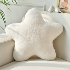 a white star pillow sitting on top of a couch next to a potted plant