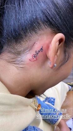 a woman with a small tattoo on her left side behind the ear that says love