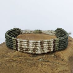 a close up of a bracelet on top of a piece of rock with a white and brown stripe