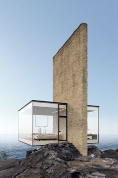 an unusual house on top of a rocky cliff overlooking the ocean with glass walls and windows