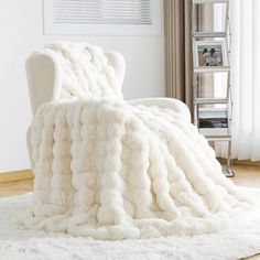 a white chair sitting on top of a rug covered in a large fluffy throw blanket