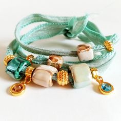 Women's bracelet in turquoise, beige and gold tones. This bohemian-style bracelet with a chic touch is made with a turquoise, aquamarine, light blue cotton ribbon that wraps around your wrist three times and is tied at the back. It is decorated with several charms of different styles, Greek porcelain beads, golden charms and two hanging light points. This bracelet has a bohemian touch but is very elegant and distinguished. Give your look a modern and youthful point with chic airs. -------------- Bracelet For Girlfriend, Bracelets Elegant, Bracelets Hippie, Boho Chic Bracelets, Cotton Bracelet, Porcelain Beads, Women Bracelets, Fabric Bracelets, Cotton Ribbon