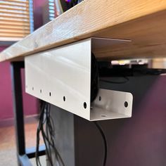 an electronic device is plugged in to the side of a wooden table with metal brackets