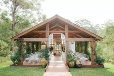 an outdoor wedding venue with white chairs and greenery on the front lawn, surrounded by trees