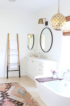 a bathroom with two mirrors and a rug on the floor in front of the bathtub