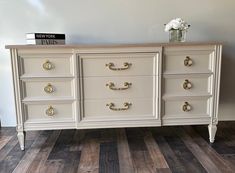 a white dresser with gold handles and drawers