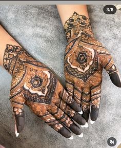 two hands with henna designs on them, one is black and the other is brown