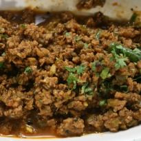 a white plate topped with meat covered in sauce and garnished with parsley