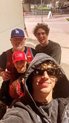 three men are taking a selfie in front of a building while wearing hats and sunglasses