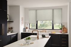 a kitchen with black cabinets and white countertops has an island in front of the window