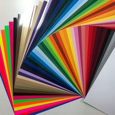 an assortment of different colors of paper on a white surface with one folded in half