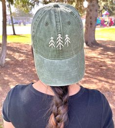 a woman wearing a hat with trees embroidered on the front and back of her head