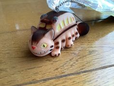 a cat figurine sitting on top of a wooden floor next to a plastic bag