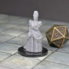 a white and gold figurine sitting on top of a table next to a dice