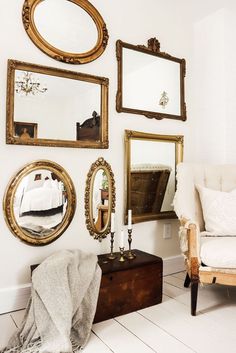 a white space with a creamy chair, a dark chest with decor and a refined mirror gallery wall with mirrors in gold frames Romantic Antique Bedroom, Antique Room Ideas Bedrooms, Antique Guest Bedroom Ideas, Bedroom Antique Decor, Interior Antique Modern, Boho Antique Bedroom, Antique Guest Bedroom, Cozy Antique Bedroom, Vintage Antique Decor