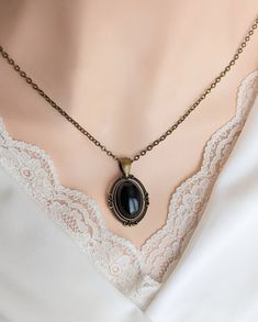 "This Obsidian necklace features a richly polished black Obsidian cabochon set in an elegant oval pendant. The vintage-inspired pendant has lovely flourish designs. The combination of the bronze pendant and inky black stone is beautiful. For those that follow Crystal beliefs: Obsidian is believed to be truth-enhancing. A strongly protective stone, people believe it forms a shield against negativity.  This would be a quintessential gift for anyone that loves natural crystal jewelry or simply the Dark Academia Jewelry, Black Pendant Necklace, Obsidian Ring, Obsidian Necklace, Victorian Pendants, Obsidian Stone, Jewelry Black, Bronze Pendant, Black Obsidian