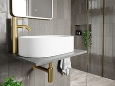 a white sink sitting under a bathroom mirror next to a green plant in a vase