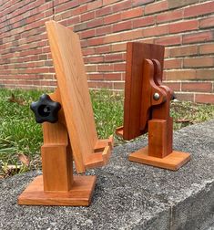 two pieces of wood sitting on top of a cement slab next to a brick wall