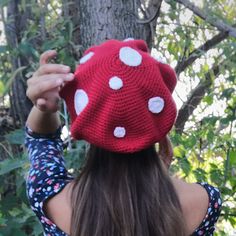 a woman wearing a red knitted mushroom hat with white polka dots on her head