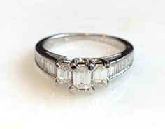 Here is a beautiful 14k white gold emerald cut diamond ring. The center stone is .20ct. with 2 side emerald cut diamonds totaling .30ct. There are also 16 baguettes in the band totaling .56ct. A beauty that will get a lot of compliments! Metal: 14K White Gold Diamonds: 1-Emerald Cut .20cttw, 2-Emerald cut .30cttw, G/H, VS, 16-side stones .56cttw, Weight: 3.8 grans Size: 6.5 SKU# 21SB080619 If you have any questions on this item, please message us! GandDJewelers.etsy.com Please note that all of o Emerald Cut Diamond Ring, Emerald Cut Diamond, Diamond Cluster Ring, Emerald Cut Diamonds, Jewelry Companies, Diamond Cluster, Cluster Ring, Yellow Gold Rings, Emerald Cut