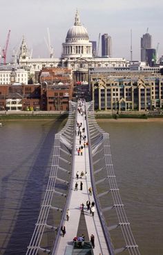 people are walking across the bridge over the water