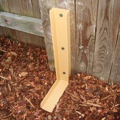 a wooden post sticking out of the ground in front of a fence and wood slats