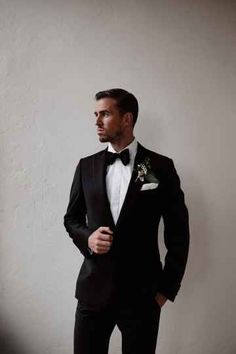 a man in a tuxedo is posing for a photo with his hands on his hips