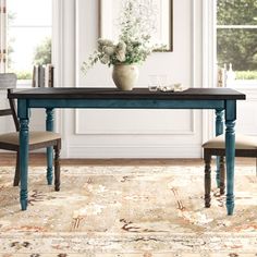 a dining room table with two chairs and a vase