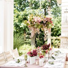 the table is set with pink flowers and white vases on it's side