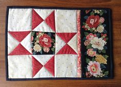 a quilted table runner with red and white flowers on it